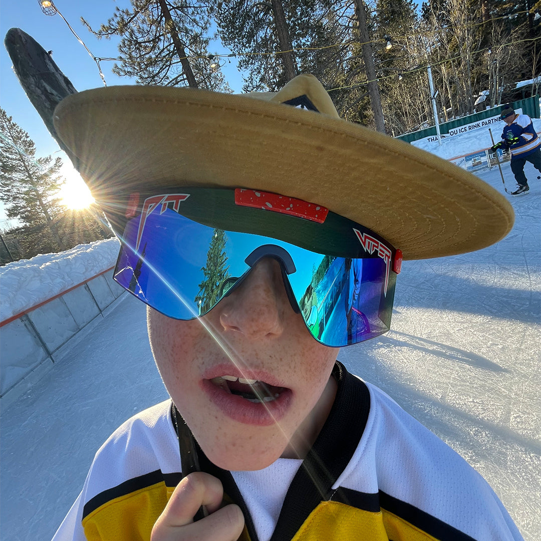 kid on an ice rink wearing blue sunglasses with a red frame - lifestyle