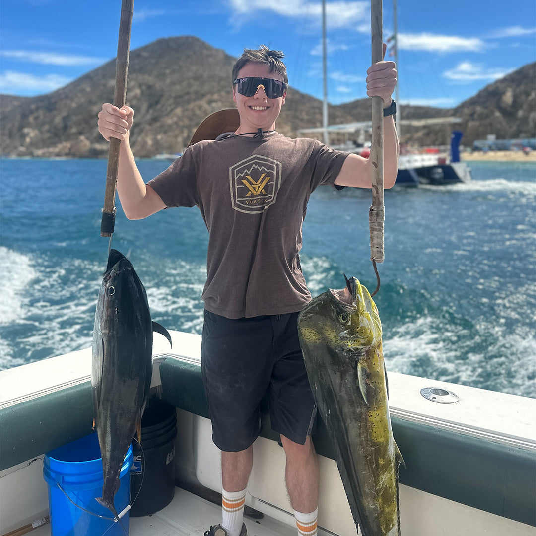 man holding two fish that he caught with black sunglasses - lifestyle