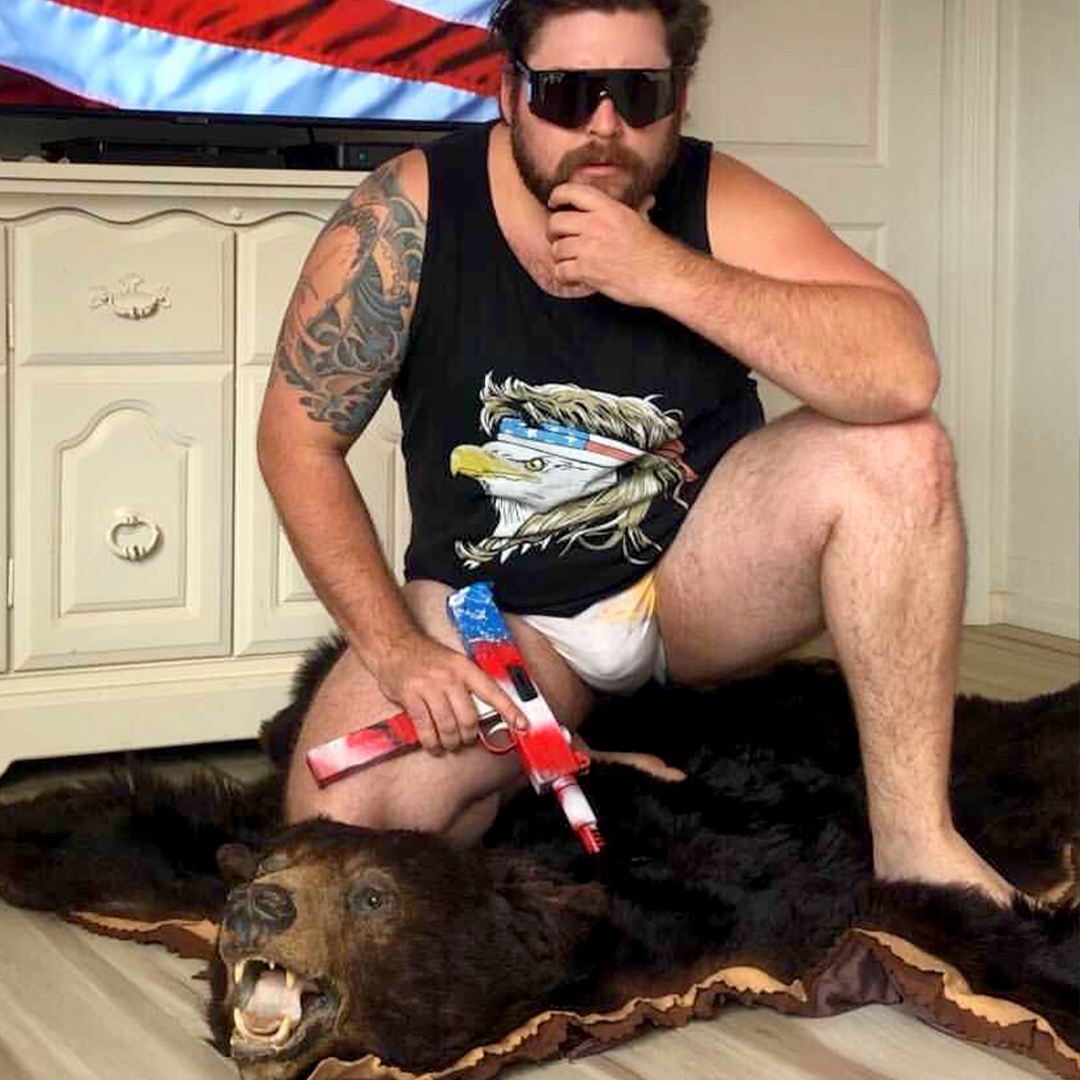 Man holding a fake gun sitting on a bear rug wearing The Black Ops 2000s - lifestyle