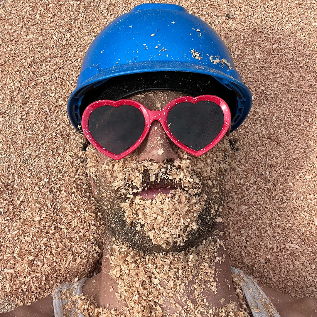 man wearing responder admirers and hard hat covered in wood chips - lifestyle